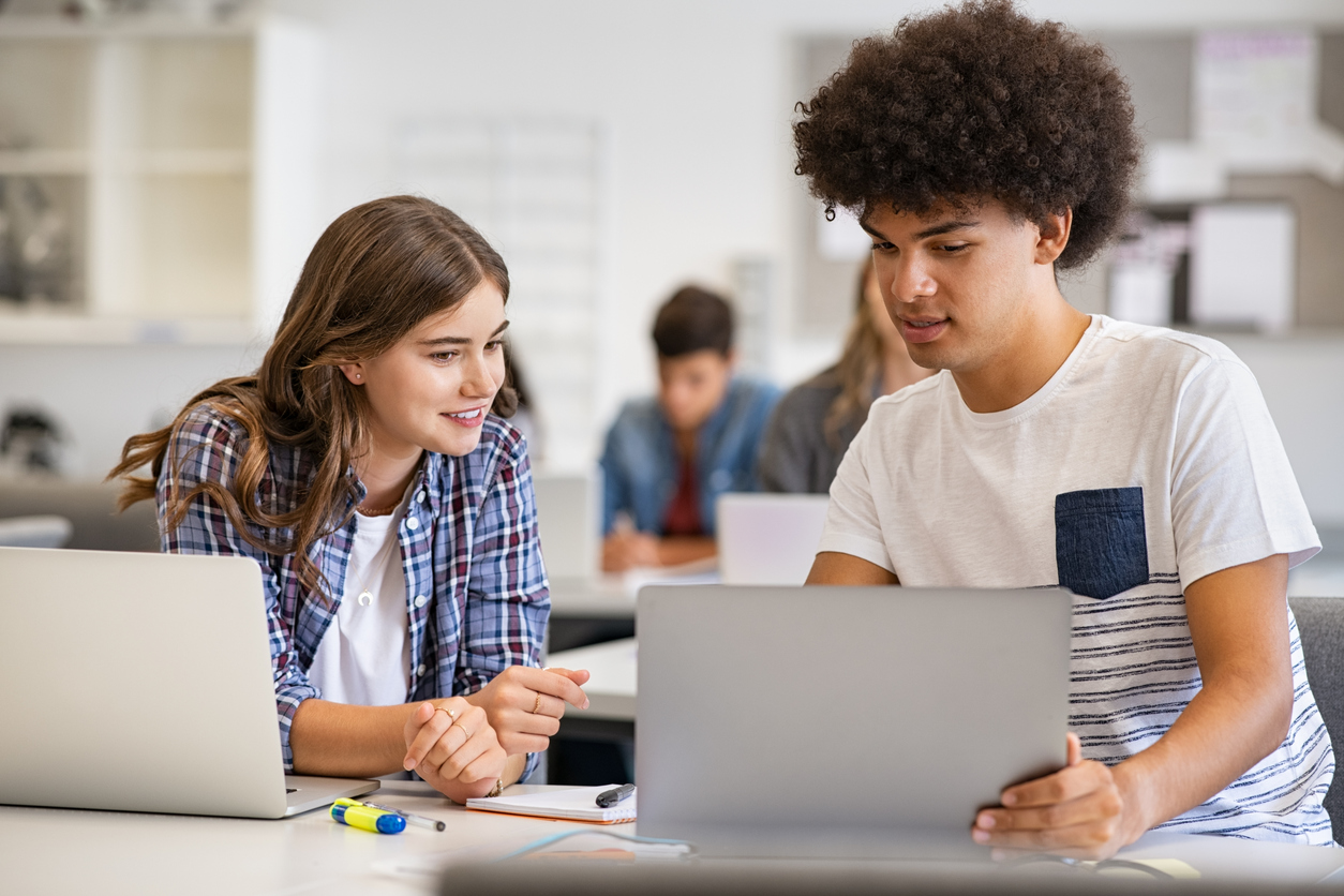 Estudantes do ensino médio na sala de aula estudando com seus notebooks.