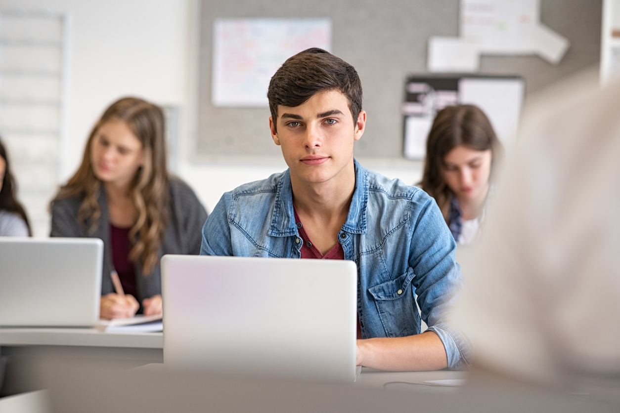 Estudante do ensino médio na sala de aula estudando com seu notebook.