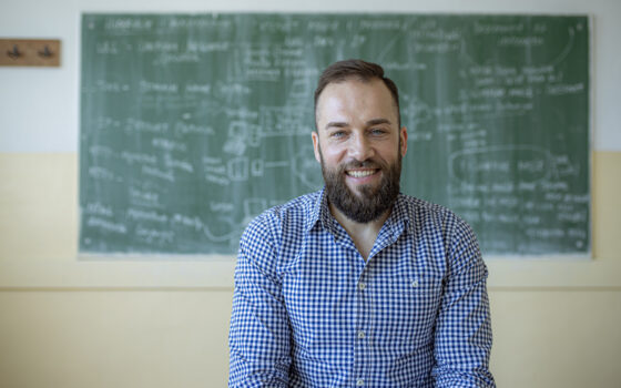 Retrato de um professor sorrindo na sala de aula.