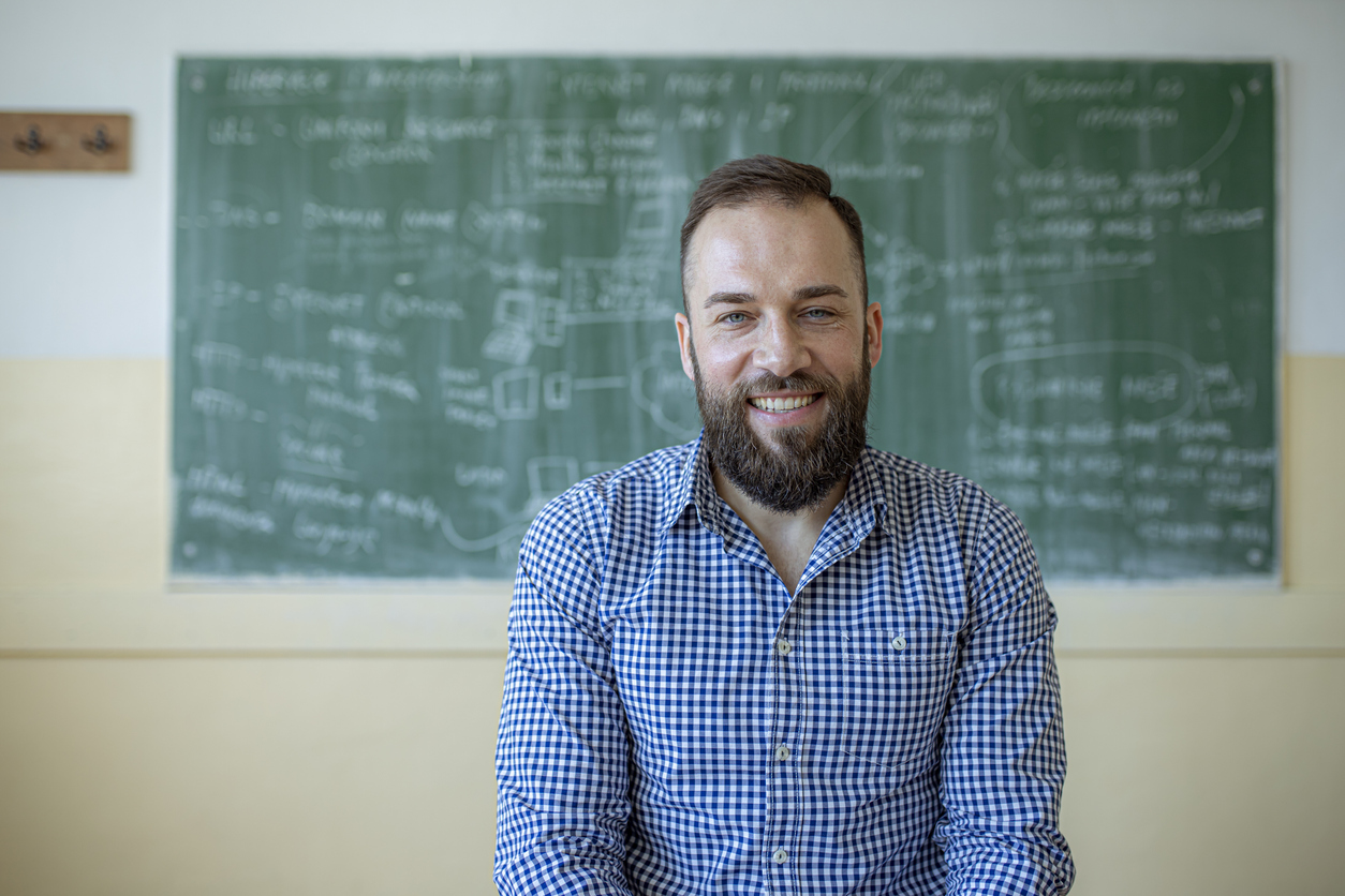 Retrato de um professor sorrindo na sala de aula.